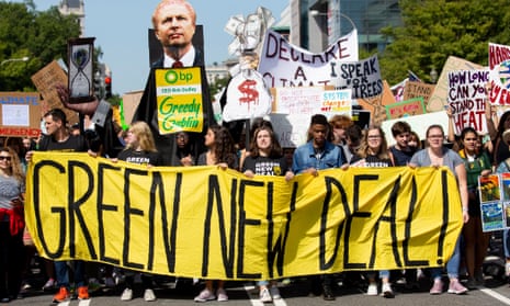 Crowd of protesters march with large 'Green New Deal' banner and placards