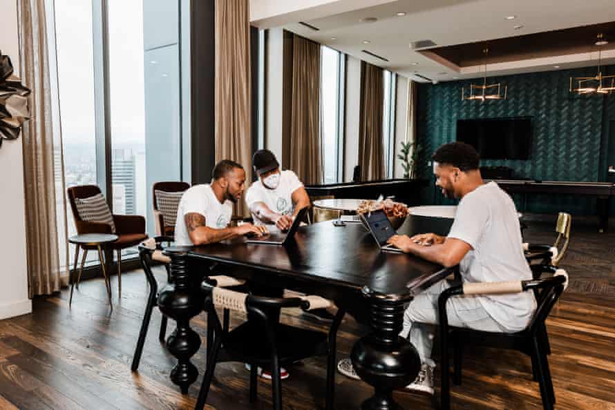 Three men work on laptops inside a large room