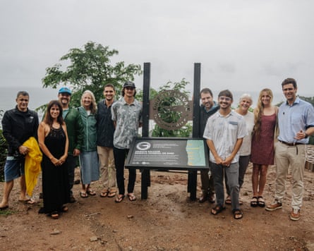 A group of people stand next to an information board on an overcast day