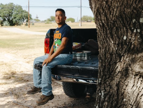 A man sits on the tailgate of his pickup truck.