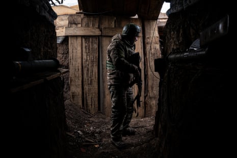 A member of Ukrainian service personnel stands inside a trench at an undisclosed location near the frontline.