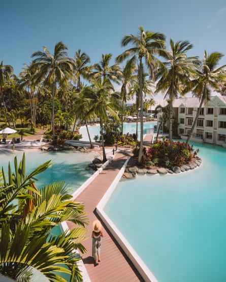 Woman walking through a lagoon-style swimming pool in lush tropical gardens
