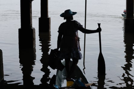 A Woman in a canoe is seen in silhouette under a jetty