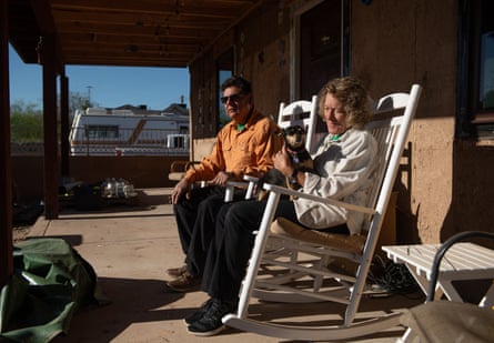 An couple sitting on white rocking chairs in their front porch