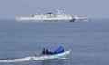 A Philippine fisherman aboard his outrigger boat sailing past a Chinese coast guard ship near the Chinese-controlled Scarborough Shoal on Wednesday