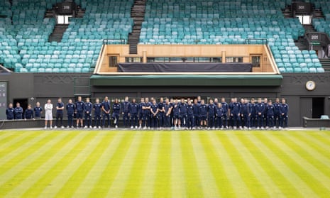 tennis club staff at Wimbledon pose for a picture beneath the royal box on Centre Court