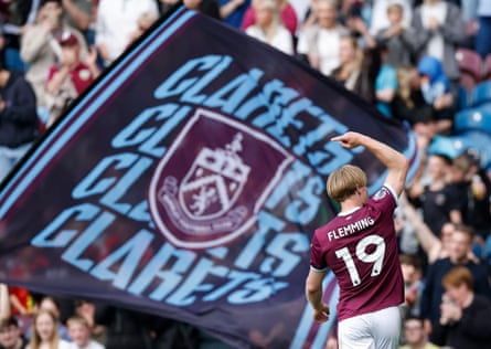 Zian Flemming celebrates scoring for Burnley, as fans wave a flag in the background.