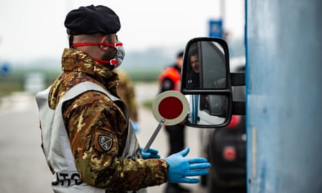 A man in military uniform and blue disposable gloves next to a vehicle at a check point in Lodi, Lombardy