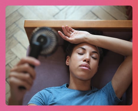 A woman lies on a yoga mat holding a small handheld fan, with one hand resting on her forehead