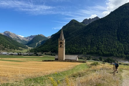 a lone church tower in a field with scenic mountain setting