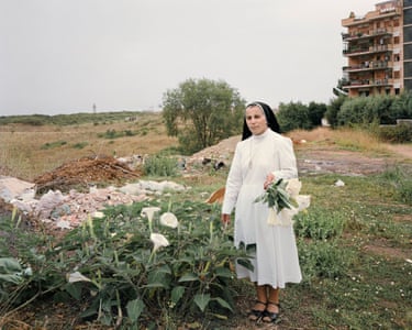 A nun picks flowers in scrubland on the edge of Rome
