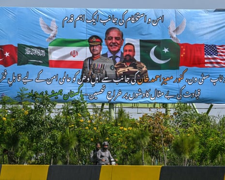 Motorcyclists ride past a billboard featuring Pakistani PM Shehbaz Sharif (centre) and army chief Field Marshal Syed Asim Munir (left) in Islamabad on 20 April 20