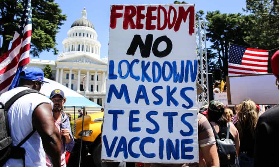 A protester holds a sign against lockdown, masks, Covid testing and vaccines in Sacramento, California, on 23 May 2020. 