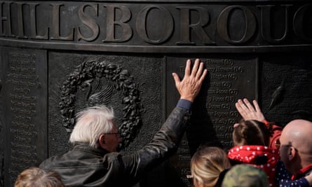 People place their hands on the Hillsborough memorial