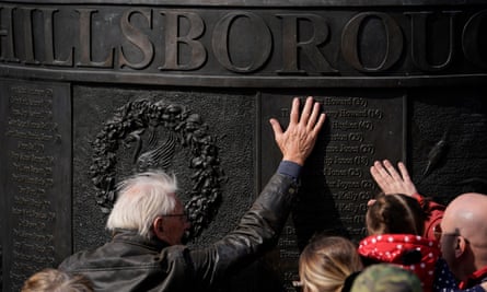 People place their hands on the Hillsborough memorial outside Saint George's Hall in Liverpool.