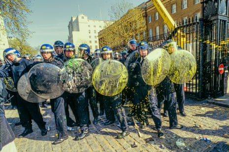 A line of police holding paint=spattered riot shields in front of them, at the March for Social Justice, London, 12 April 1997