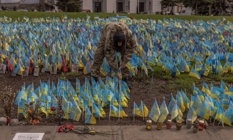 A man places Ukrainian flags to commemorate soldiers killed during the war in Kyiv, Ukraine.