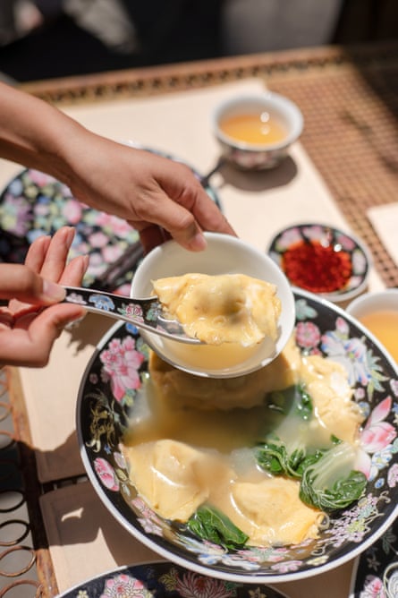 A hand spooning an egg-wrapped dumpling into a bowl.
