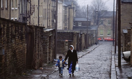 A Muslim woman and her son walk down a cobbled street in Bradford
