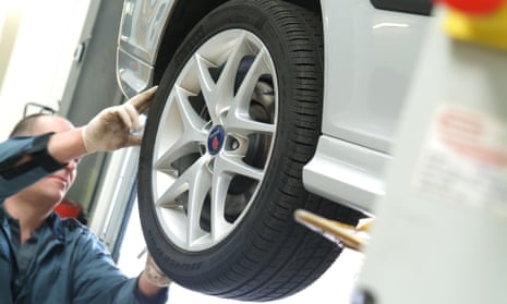 garage mechanic checking tyre legal tread