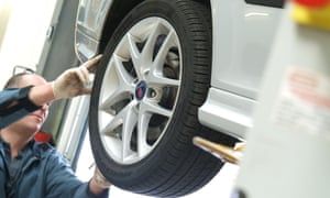 A garage mechanic checks tread depth on a tyre.