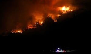 Flames work through trees near a road block as the Cameron Peak fire, the largest in Colorado’s history, burns outside Estes Park.