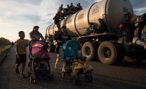 Migrants part of the caravan push strollers on the road.