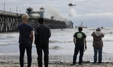 Pier catches fire in Southern California, Oceanside, CA, United States - 25 Apr 2024<br>Mandatory Credit: Photo by Hayne Palmour IV/REX/Shutterstock (14450777l) People watch a helicopter drop water as fire crews fight a fire burning at the end of the Oceanside Municipal Pier in Oceanside, California on Thursday, April 25, 2024. The fire started at a vacant restaurant at the end of the pier causing significant damage. No injuries were reported. Pier catches fire in Southern California, Oceanside, CA, United States - 25 Apr 2024