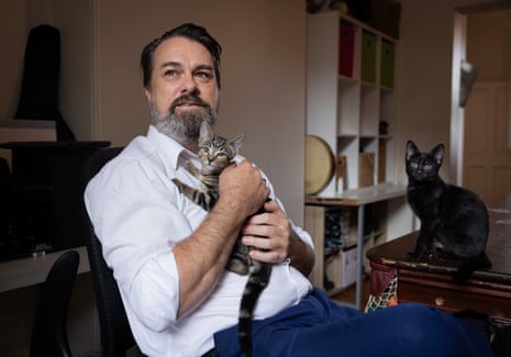 A man in a living room with two young cats