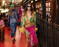 A model in a vibrant dress and dark sunglasses walks the Valentino catwalk in a library. Photo: Abdul Saboor/Reuters