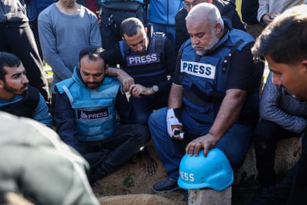 Several sorrowful Arab men in bullet-proof vests marked ‘press’ kneel at a graveside. Wael rests his hand on his son’s blue ‘press’ helmet