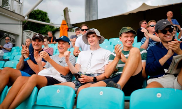 A group of friends sit together – without wearing masks – though spaces were left between rows of seats at the Oval.
