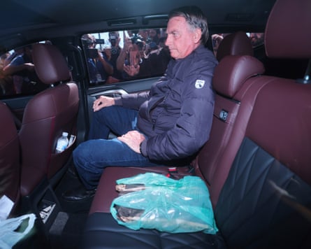 Jair Bolsonaro sitting in the backseat of a vehicle