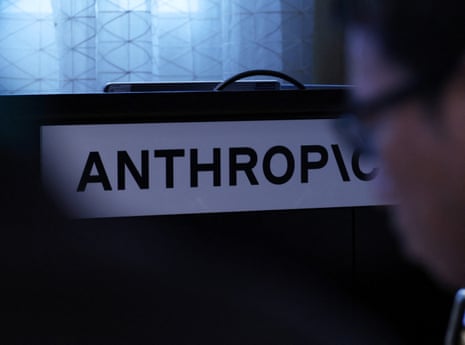Anthropic's logo sign is displayed near a person at a media briefing