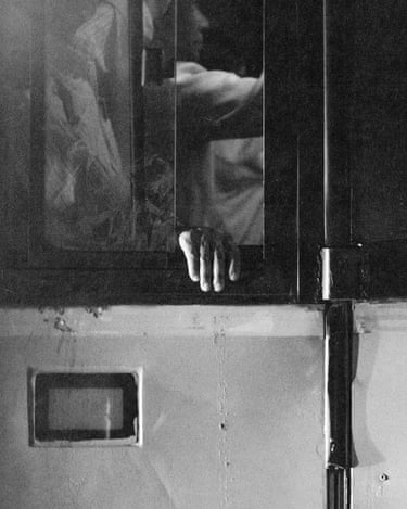 A man hangs on to an open window in the mid-summer heat of New Delhi, a photograph by Kartikeya Manan