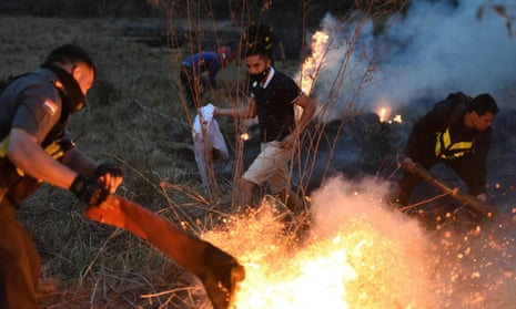 Members of Paraguay’s highway patrol and local residents try to extinguish a fire on 27 September in San Bernardino, east of Asuncion, Paraguay.