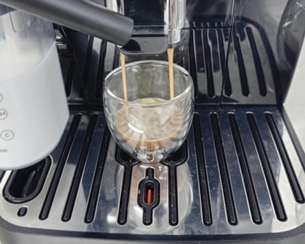 Delonghi Magnifica Start, closeup of the machine’s metal drip tray and a glass espresso cup.