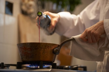 A chef is holding a pan in one hand while pouring red wine with the other