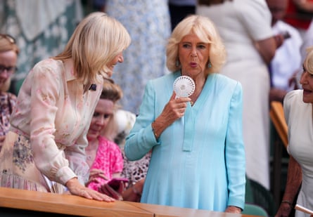 Queen Camilla cools herself with an electric hand fan at Wimbledon
