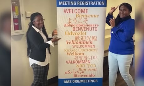 Two teens stand next to a sign for the American Mathematical Society meeting.