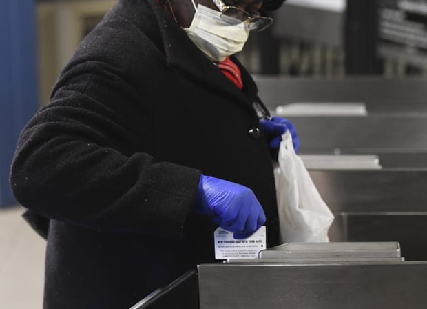 A woman wears gloves while swiping her fare card in the New York subway.