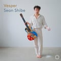 An album cover with a man wearing white clothes holding a colourful guitar