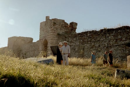 Two visitors stand reading an information panel at an old castle