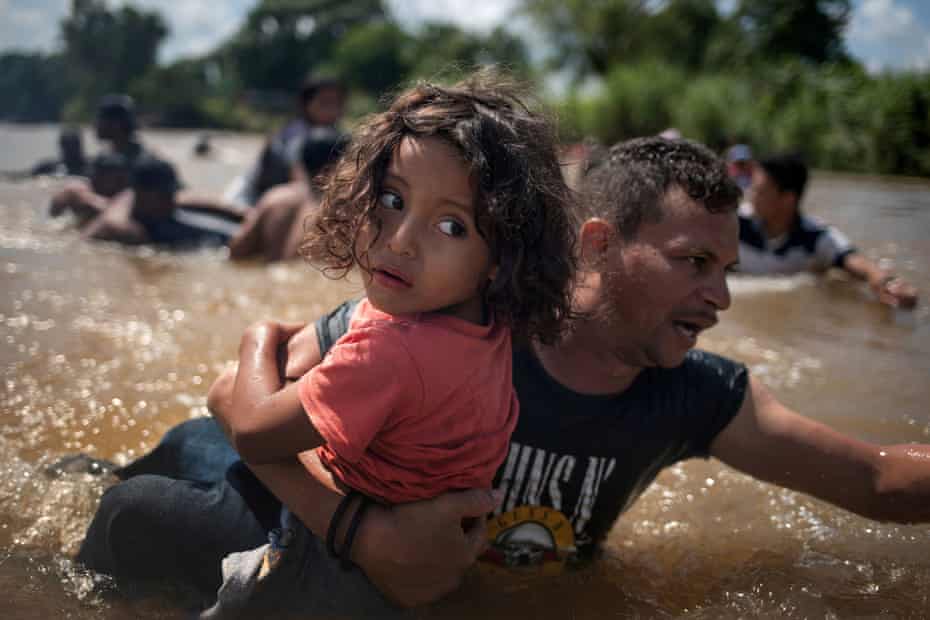 Luis Acosta holds 5-year-old Angel Jesus, both from Honduras, as a caravan of migrants from central America moving towards the US cross through the Suchiate River into Mexico from Guatemala. 29 October, 2018.