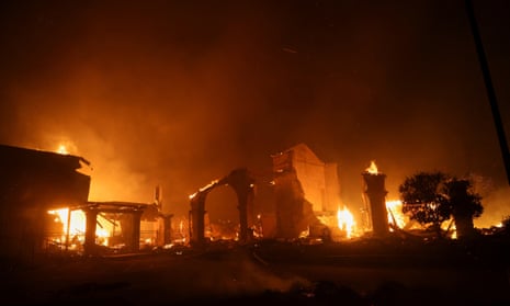 Flames rise from structures as the Eaton Fire burns in Pasadena, California.