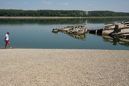 A man walks along a dried up riverbed past the wreckage of a second world war German warship