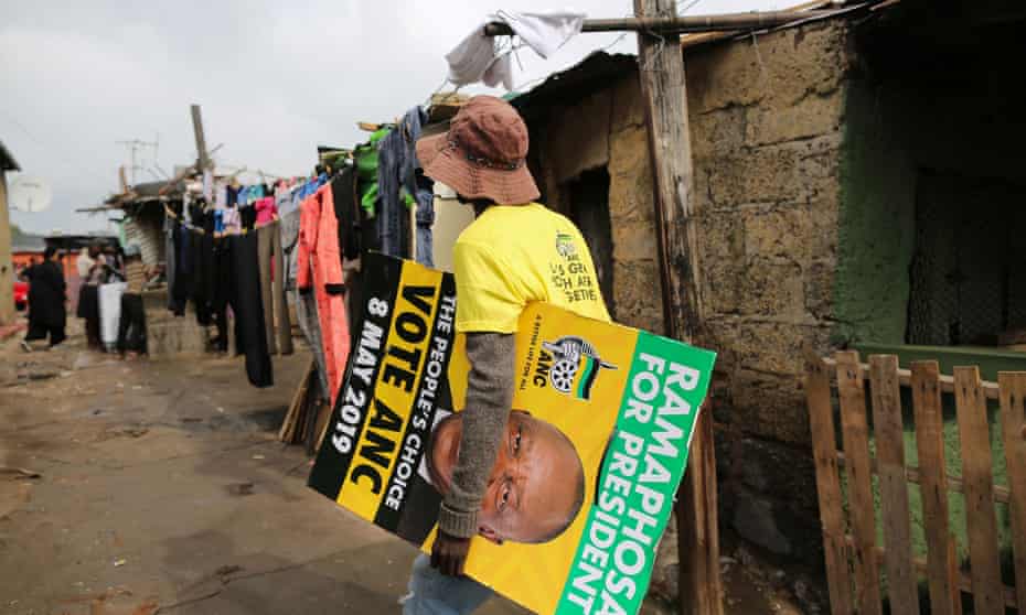 A man carries an ANC campaign poster through Alexandra township in Johannesburg