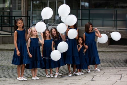Young models wearing navy summer dresses and carrying white balloons at the Edeline Lee show.