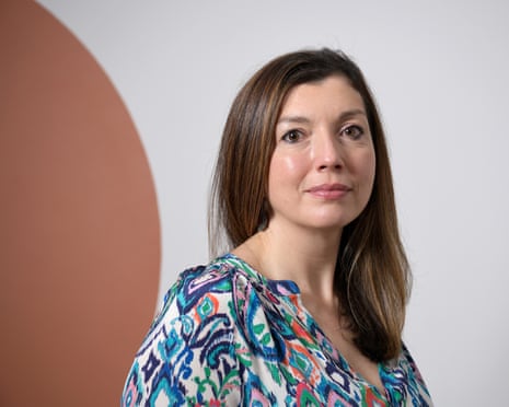 Sara Husseini with long brown hair wearing a colorful patterned top against a white backdrop