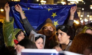 People hold EU flags in the rain